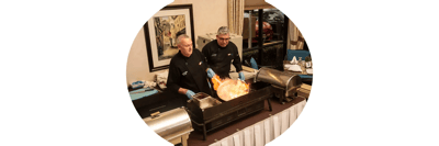 Two chefs preparing food at an event.