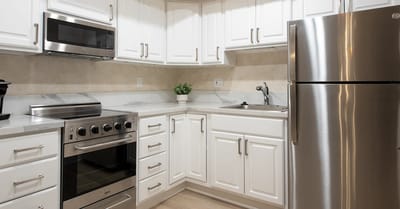 Modern kitchen with white cabinets and appliances.