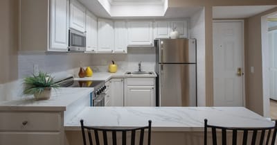 Modern kitchen with white cabinets and stainless steel appliances.