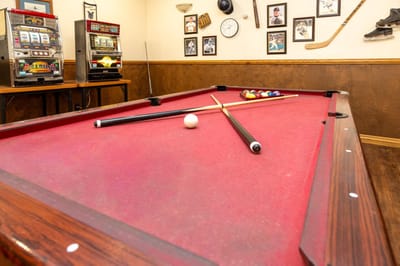 Pool table with cue sticks and balls in a rec room