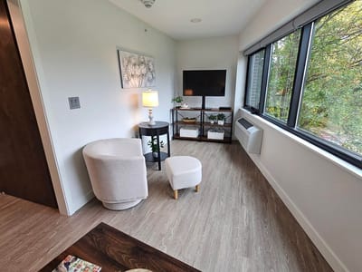 Cozy corner of a resident's room with a chair and TV.