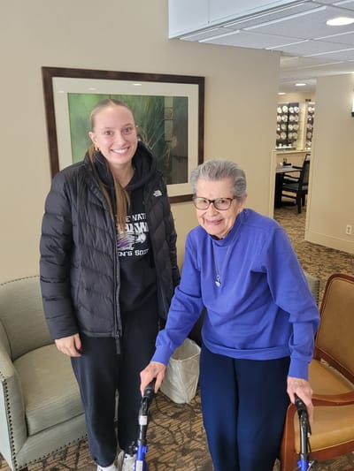 Resident and staff member smiling in common area.