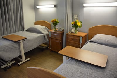 Shared resident room with bedside tables and flowers