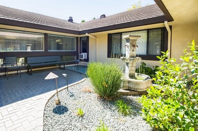 A serene outdoor courtyard with a fountain and landscaping