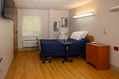 A private resident room with a bed and bedside table