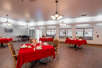 Dining room set up for a meal with red tablecloths