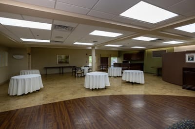 A spacious activity room with round tables and chairs