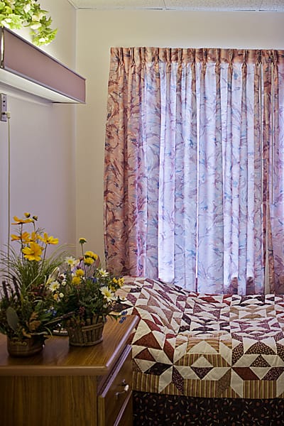Cozy resident room with a quilt and flowers