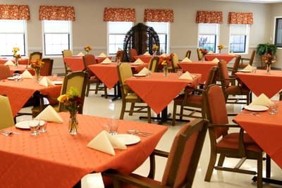 Dining area with orange table settings and floral centerpieces