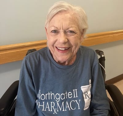 Smiling resident wearing a pharmacy volunteer shirt