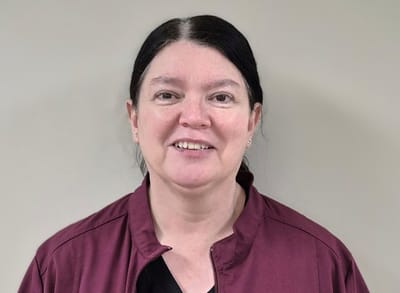 Staff member smiling in a healthcare uniform