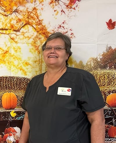 Staff member smiling in front of a fall-themed backdrop.