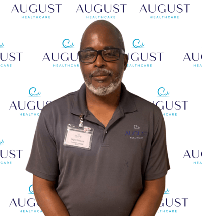 Staff member in front of facility logo background.