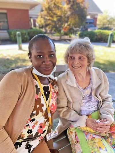 Resident and staff member smiling outdoors