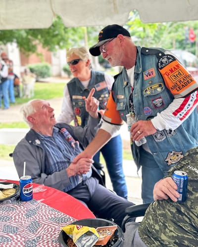 Veterans enjoying a meal and conversation at an outdoor event.