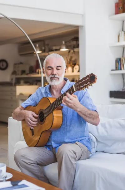 Senior man playing guitar in a cozy room