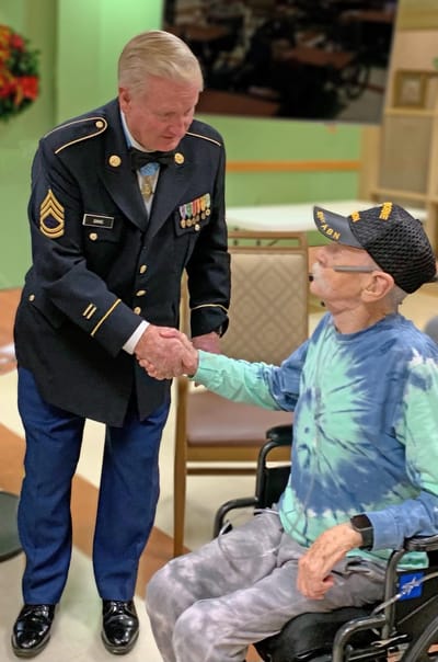 Veteran in military uniform greeting resident