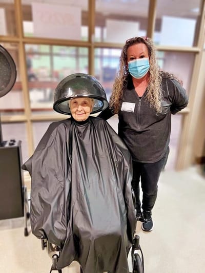 Resident enjoying a hair salon service with staff.