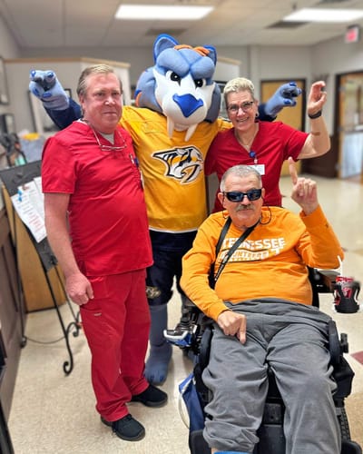 Staff and resident with a mascot in a common area