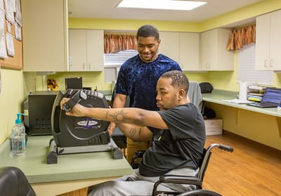 A staff member assisting a resident with therapy equipment.