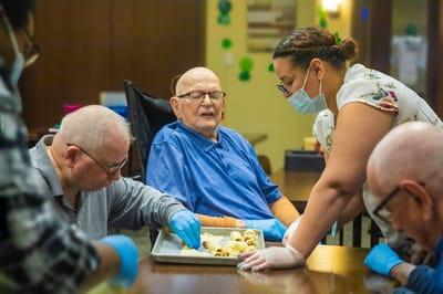 Residents engaging in an activity with staff assistance.