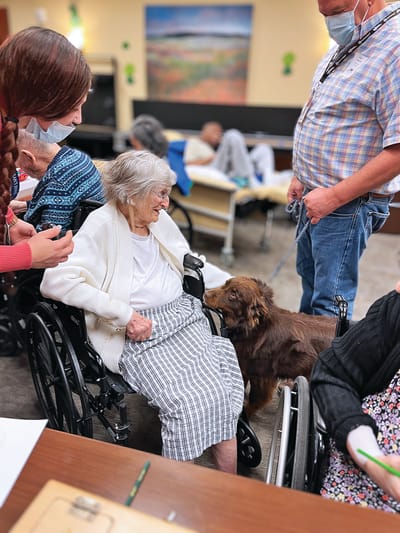 Residents interacting with a dog in a communal area.