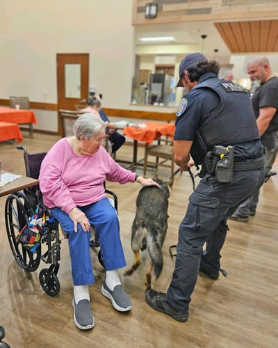 Resident interacting with police officer and dog in common area