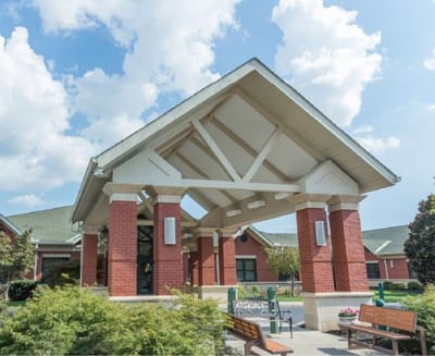 Entrance of a senior living facility with outdoor seating.
