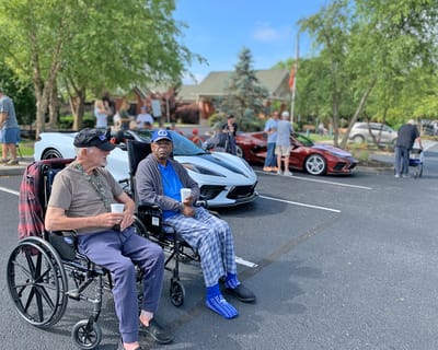 Residents enjoying a car show in the parking lot.