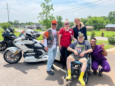 Residents and staff posing with a motorcycle