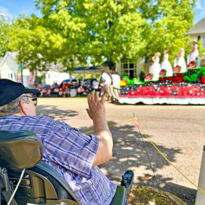 Resident waving at a community parade event.