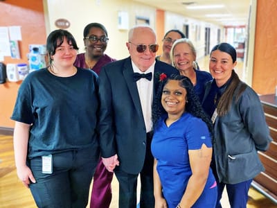 Residents and staff posing together in the hallway.