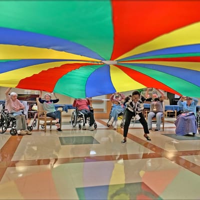 Residents participating in a colorful indoor activity with a parachute.