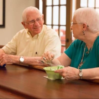 Two seniors sharing a meal in a common area.