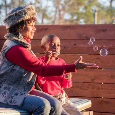 A woman and child playing with bubbles outdoors.