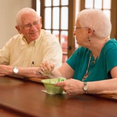 Two seniors enjoying ice cream at a counter.