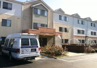 Exterior view of assisted living facility with shuttle van.