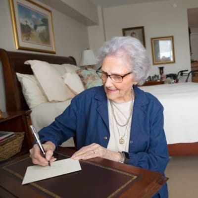 Senior resident writing in her room.