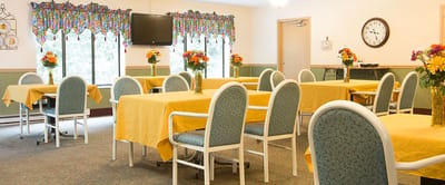 Dining room setup with yellow tables and floral centerpieces
