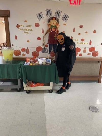Staff member in a Halloween costume with treats