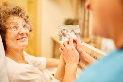 A senior woman smiling while holding a photo