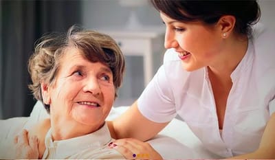 A caregiver smiling at a senior resident indoors