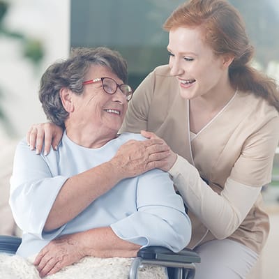 A caregiver and a smiling resident in a bright room