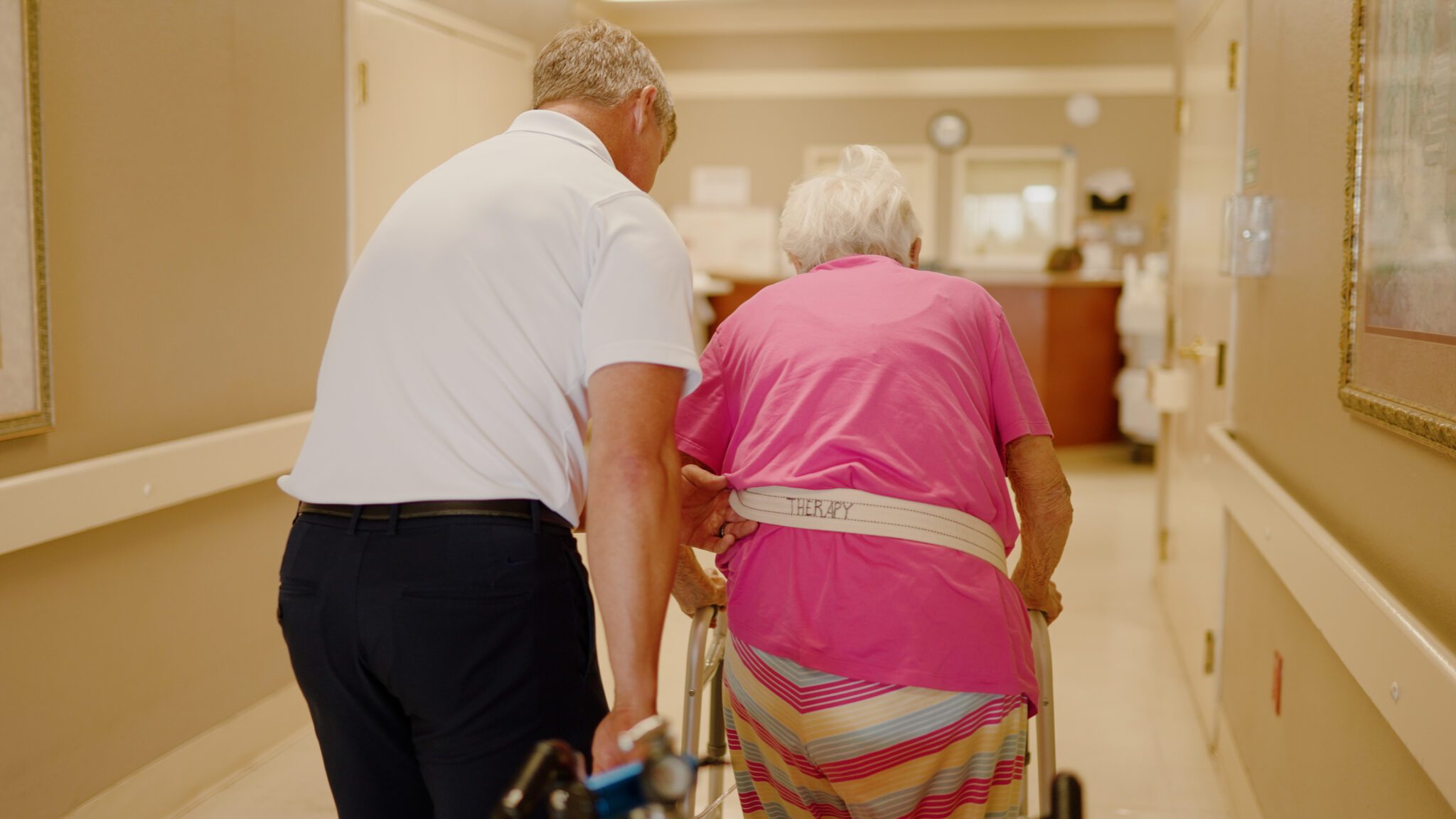 A staff member assisting a resident in a hallway
