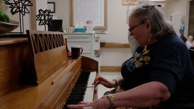 Senior resident playing piano in an activity room