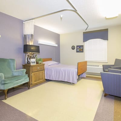 A cozy resident room with a bed and chair