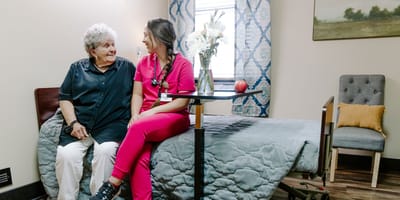 A resident and staff member smiling in a cozy room