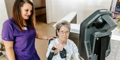 Staff assisting a resident with equipment in an interior space