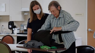 Staff assisting a resident with clothing in a care facility