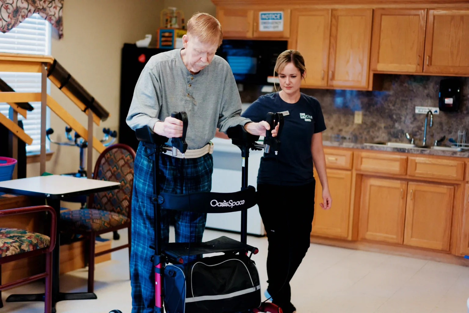 Employee assisting a resident with a walker in a cozy interior space